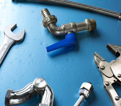 tools for plumbing featuring a metal valve adjustable wrench pipe fittings and a blue lever in a workshop setting