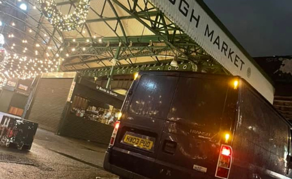 dark van parked at Borough Market at night with festive lights and market stalls in the background two more deliveries