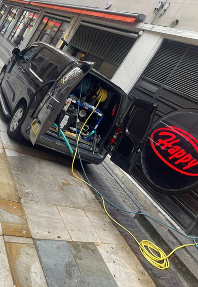 a van with open doors displaying equipment and hoses parked near a Happy sign in a city setting service vehicle for maintenance tasks